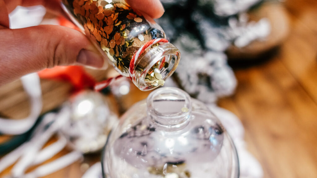 gold glitter being poured into clear ornament