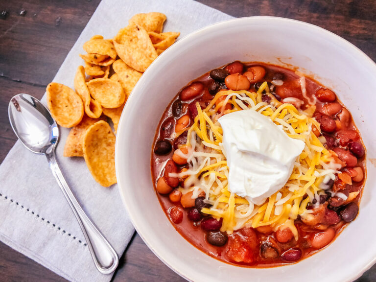 bean chili in a white bowl with shredded cheese and sour cream on top